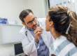 Médecin ORL réalisant un examen de la gorge d'une patiente lors d'une consultation médicale en cabinet.