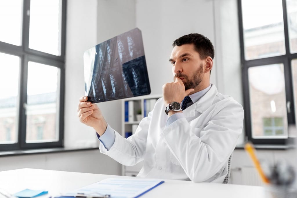 Médecin radiologue observant une radiographie de la colonne vertébrale pour établir un diagnostic des troubles du rachis.