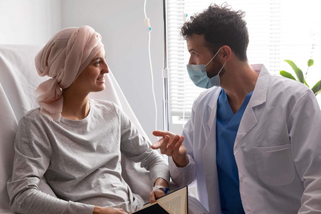 Médecin oncologue échangeant avec une patiente hospitalisée atteinte d'un cancer lors d'un suivi en service d'oncologie.
