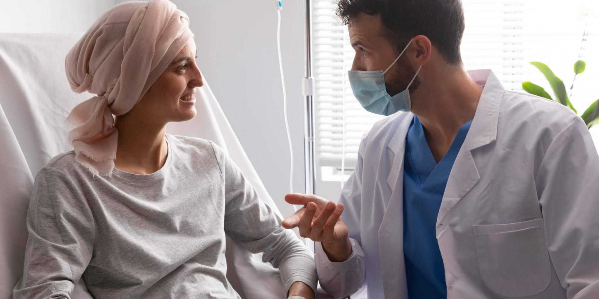 Médecin échangeant avec une patiente hospitalisée atteinte d'un cancer lors d'un suivi en service d'oncologie.